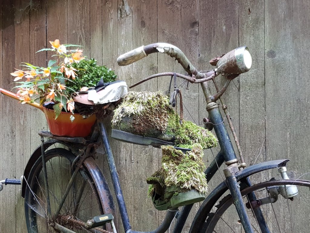 Dekoratives retro-vintage-modell fahrrad ausgestatteter korb blumengarten am sonnigen sommertag